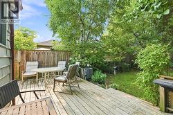 Wood-finish deck with a privacy fence, mature trees, and a grassy area - 