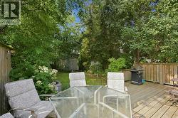 Expansive wooden deck with a privacy fence, overlooking a lush green lawn, mature trees, and a storage shed - 