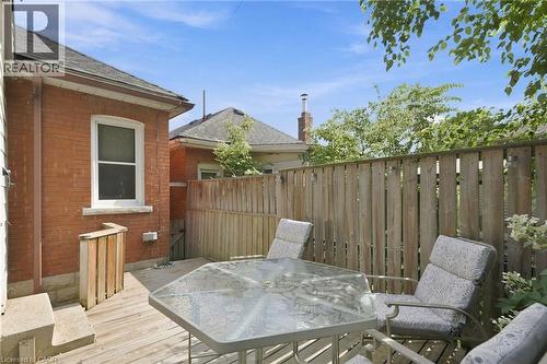 Wood-finish deck with a privacy fence, featuring a red brick exterior and a white-trimmed window - 58 Edinburgh Avenue, Hamilton, ON - Outdoor With Deck Patio Veranda With Exterior