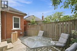 Wood-finish deck with a privacy fence, featuring a red brick exterior and a white-trimmed window - 