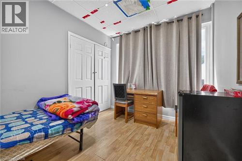 Room featuring wood-finish flooring, drop ceiling, and light gray wall paint - 1292 Barton Street E, Hamilton, ON 