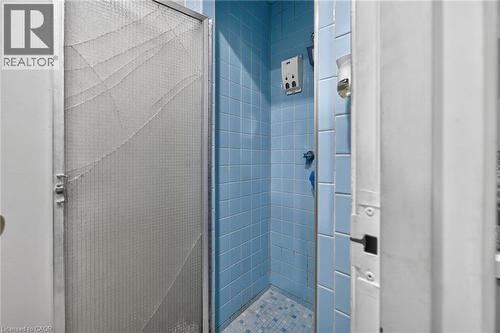 Shower enclosure with blue wall tiles and a patterned tile floor - 1292 Barton Street E, Hamilton, ON 