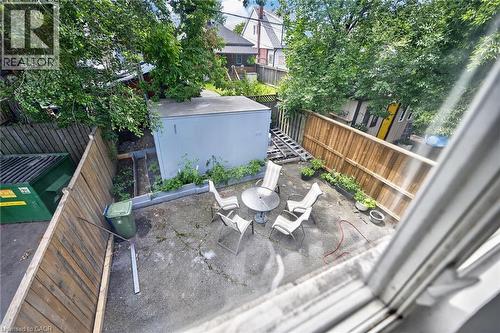 Fenced backyard space featuring a concrete patio area, mature trees, and a detached shed - 1292 Barton Street E, Hamilton, ON 