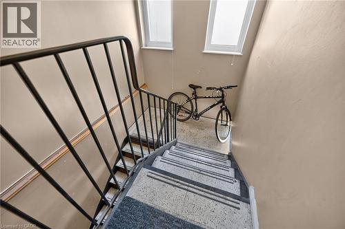 Stairwell with light neutral wall paint, a black metal handrail, and terrazzo-style treads - 1292 Barton Street E, Hamilton, ON 