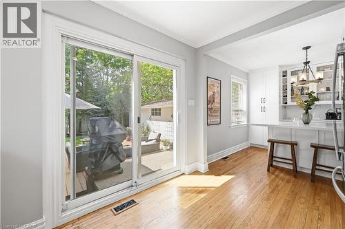 Sliding glass door opening to a private patio space with a manicured lawn beyond - 18 Ipswich Place, Hamilton, ON - Indoor Photo Showing Other Room