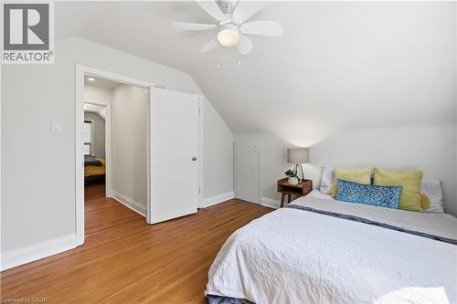 Attic room featuring hardwood flooring, white walls, angled ceilings, and a ceiling fan with integrated lighting - 18 Ipswich Place, Hamilton, ON - Indoor Photo Showing Bedroom