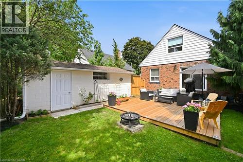 Expansive backyard featuring a large wooden deck, a built-in fire pit, manicured lawn, and mature perimeter trees - 18 Ipswich Place, Hamilton, ON - Outdoor With Deck Patio Veranda With Exterior