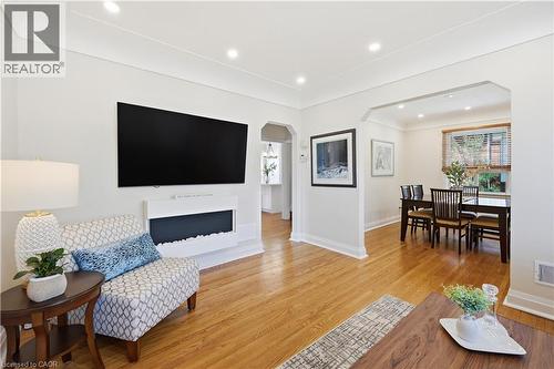 Bright living area featuring wood-finish flooring, recessed lighting, and a built-in wall-mounted electric fireplace - 18 Ipswich Place, Hamilton, ON - Indoor Photo Showing Living Room With Fireplace
