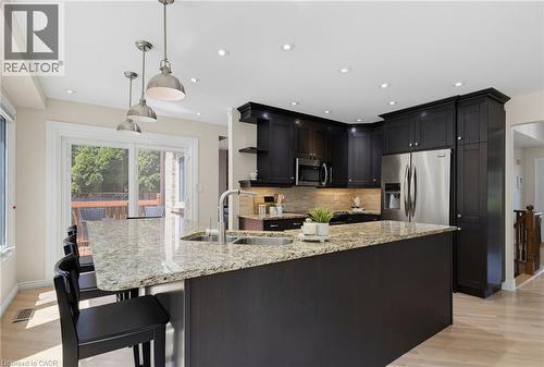 Modern kitchen featuring a granite-topped island with an undermount sink and seating for three - 2188 Bader Crescent, Burlington, ON - Indoor Photo Showing Kitchen With Stainless Steel Kitchen With Double Sink With Upgraded Kitchen