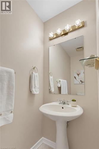 Pedestal sink with chrome fixtures, framed mirror, and a decorative vanity light bar - 2188 Bader Crescent, Burlington, ON - Indoor Photo Showing Bathroom