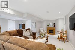 Spacious lower-level living area with recessed lighting, light-toned walls, and a built-in fireplace featuring a wood surround - 