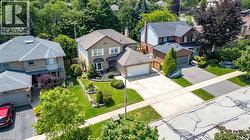 Brick two-story residence featuring a bay window, attached garage, and landscaped front yard with mature shrubbery - 