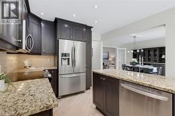 Kitchen featuring rich wood cabinetry, stainless steel appliances, granite countertops, and a tiled backsplash - 