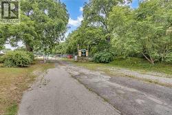 Gated entry with chain-link fencing, mature trees, and natural landscaping - 