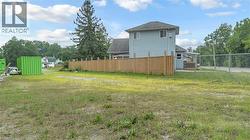 Spacious lot featuring a partial privacy fence, chain-link fencing, and mature trees on the perimeter - 
