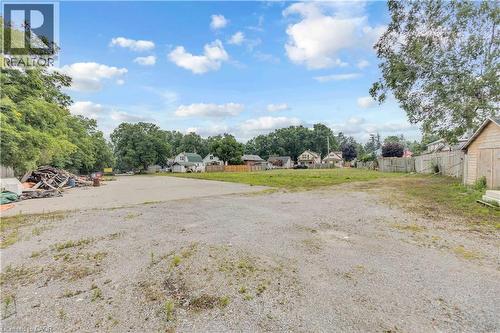 Expansive gravel lot with surrounding mature trees and partial fencing - 9 James Street, Simcoe, ON 