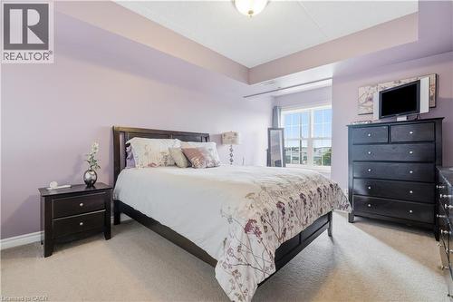 Spacious bedroom featuring light-colored carpeting, a large window with multiple panes, and a tray ceiling - 2035 Appleby Line Unit# 307, Burlington, ON - Indoor Photo Showing Bedroom