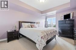 Spacious bedroom featuring light-colored carpeting, a large window with multiple panes, and a tray ceiling - 