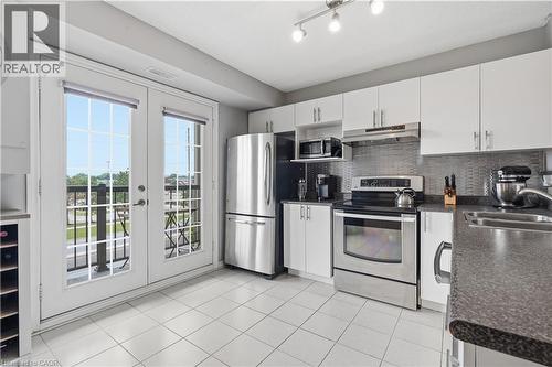 Kitchen featuring white cabinetry, stainless steel appliances, textured backsplash, and track lighting - 2035 Appleby Line Unit# 307, Burlington, ON - Indoor Photo Showing Kitchen