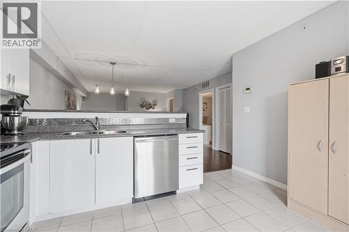 Kitchen featuring white cabinetry, stainless steel dishwasher, double basin sink, and a speckled countertop with a tiled backsplash - 2035 Appleby Line Unit# 307, Burlington, ON - Indoor Photo Showing Kitchen With Double Sink