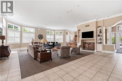 Spacious common area featuring light-toned tile flooring, extensive fenestration with horizontal blinds, and a built-in media center - 2035 Appleby Line Unit# 307, Burlington, ON - Indoor With Fireplace