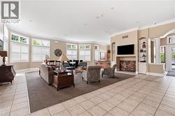 Spacious common area featuring light-toned tile flooring, extensive fenestration with horizontal blinds, and a built-in media center - 