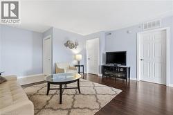 Living area featuring dark wood-finish flooring, light blue wall paint, white baseboards, and two white panel doors - 