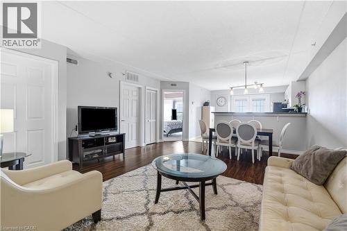 Open-concept living space featuring wood-finish flooring, light grey wall paint, and white trim - 2035 Appleby Line Unit# 307, Burlington, ON - Indoor Photo Showing Living Room