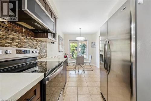 Kitchen featuring stainless steel appliances, tile backsplash, dark wood-finish cabinetry, and light countertops - 36 Van Fleet Terrace, Milton, ON - Indoor Photo Showing Kitchen With Upgraded Kitchen
