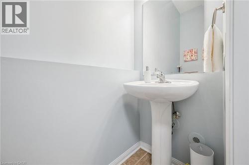White pedestal sink with a chrome faucet, set against light blue walls and brown floor tiling - 36 Van Fleet Terrace, Milton, ON - Indoor Photo Showing Bathroom