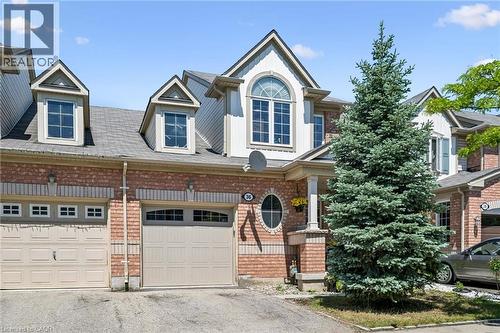 Brick and siding exterior featuring gabled dormers, an arched window, and a prominent evergreen tree - 36 Van Fleet Terrace, Milton, ON - Outdoor