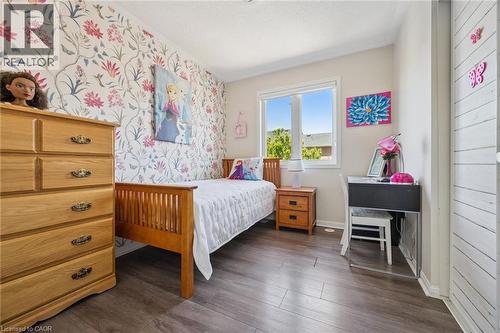 Room featuring wood-finish flooring, a double-hung window, and a accent wall with floral wallpaper - 36 Van Fleet Terrace, Milton, ON - Indoor Photo Showing Bedroom