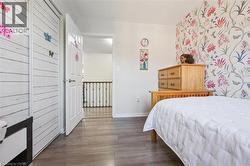 Room featuring wood-finish flooring, a wall with floral wallpaper, and a white paneled closet - 