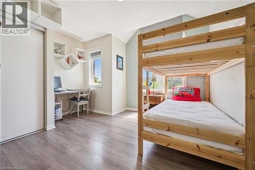 Bright room featuring wood-finish flooring, a built-in desk area with a window, white floating shelves, and a large sliding closet - 36 Van Fleet Terrace, Milton, ON - Indoor Photo Showing Bedroom