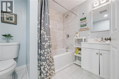 Bathroom featuring a white vanity with integrated sink, a built-in tub with tile surround, and a wall-mounted mirror - 36 Van Fleet Terrace, Milton, ON - Indoor Photo Showing Bathroom
