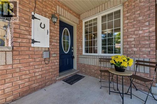 Brick exterior featuring a dark blue oval-paneled entry door with an overhead light fixture - 36 Van Fleet Terrace, Milton, ON - Outdoor With Exterior