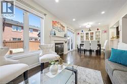 Open-concept living space featuring wood-finish flooring, a contemporary fireplace with a white mantel, and large windows - 