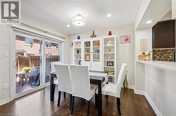 Dining area featuring wood-finish flooring, white built-in shelving, a modern ceiling light, and recessed lighting - 