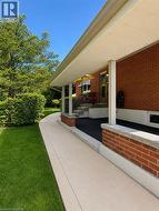 Inviting covered front porch with brick accents, concrete steps, and a concrete walkway - 