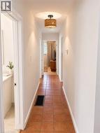 Hallway featuring terra cotta tile flooring, light-toned wall paint, recessed lighting, and a drum-style ceiling fixture - 