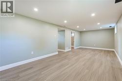 Spacious open area featuring recessed lighting, light wood-finish flooring, and light-toned walls with white baseboards - 