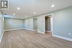 Spacious interior with light wood-finish flooring, recessed lighting, light green walls, and white trim - 