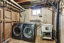 Laundry area featuring wood-finish flooring, a utility sink, and exposed block wall construction - 
