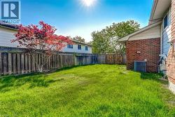 Expansive backyard featuring a green lawn, wood privacy fencing, and a mature tree with vibrant red foliage - 
