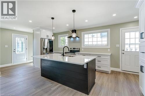 Bright kitchen featuring a dark island with white countertop, stainless steel appliances, wood-finish flooring, and recessed ceiling lighting - 191 Glenmor Drive, Caledonia, ON - Indoor Photo Showing Kitchen With Upgraded Kitchen