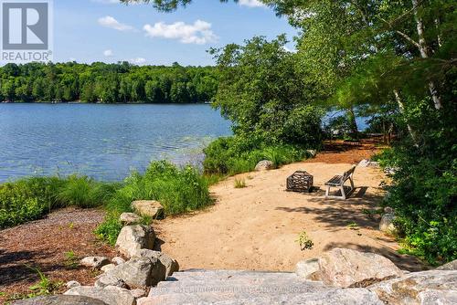 Beach with seating & firepit area - 1023 Mccabe Road, Lake Of Bays, ON - Outdoor With Body Of Water
