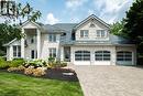 Stone veneer exterior featuring a three-car garage with arched glass panel doors, a metal tile roof, and a paver driveway - 44 St Andrew'S Drive, Brantford, ON  - Outdoor With Facade 