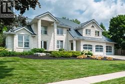 Two-story residence featuring light-colored stone exterior and a dark-colored shingled roof - 
