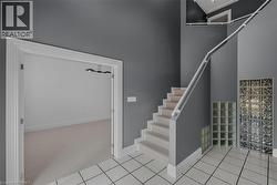 Entryway featuring a carpeted staircase, extensive glass block accents, and light-toned tile flooring - 
