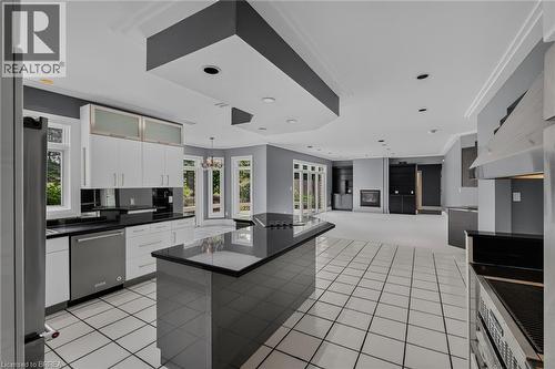Spacious kitchen featuring an expansive center island, white cabinetry, integrated stainless steel appliances, and large format white tile flooring - 44 St Andrew'S Drive, Brantford, ON - Indoor